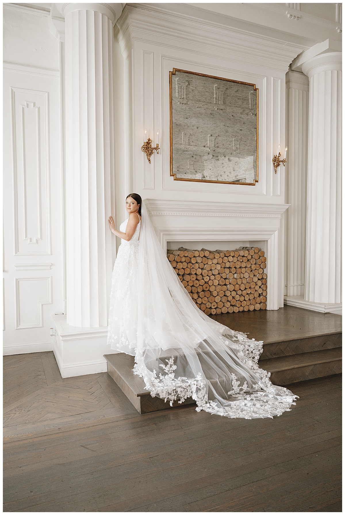 "Bride in a flowing white gown with a cathedral veil, holding a bouquet, standing gracefully in soft natural light.