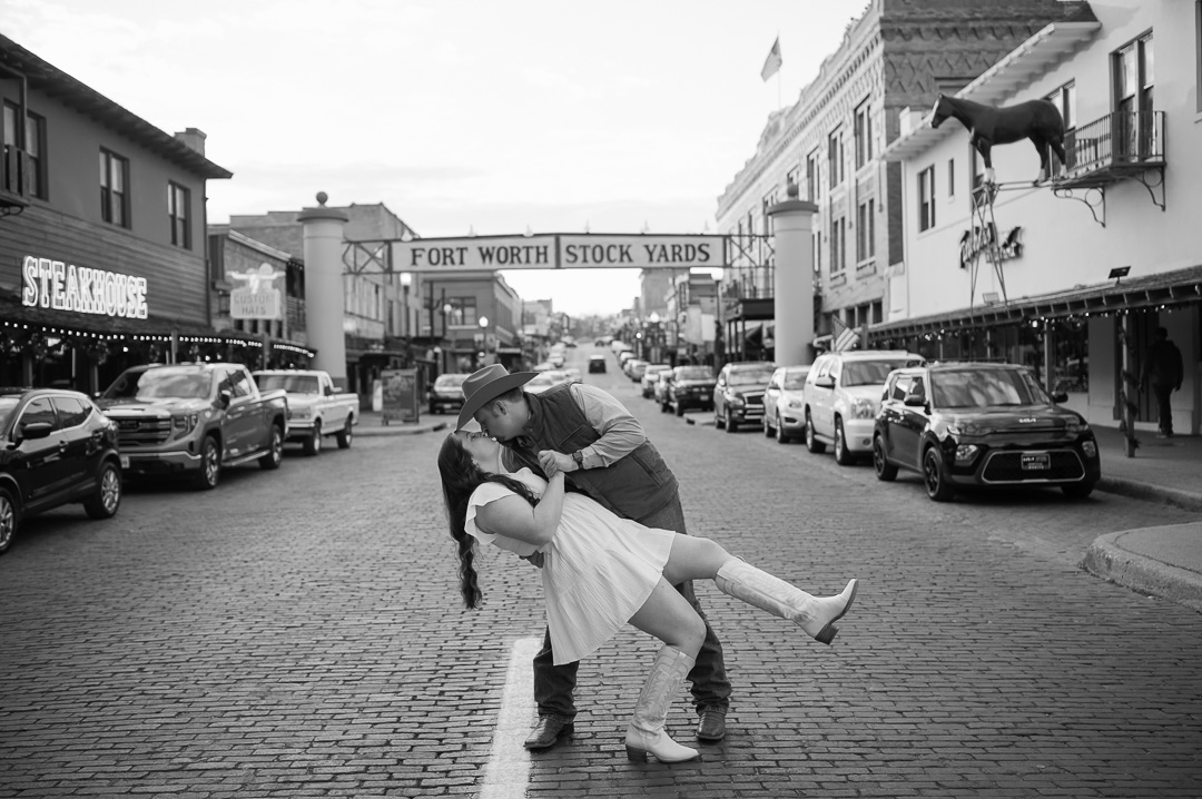 couple kissing in front of the fort worth stockyards sign.